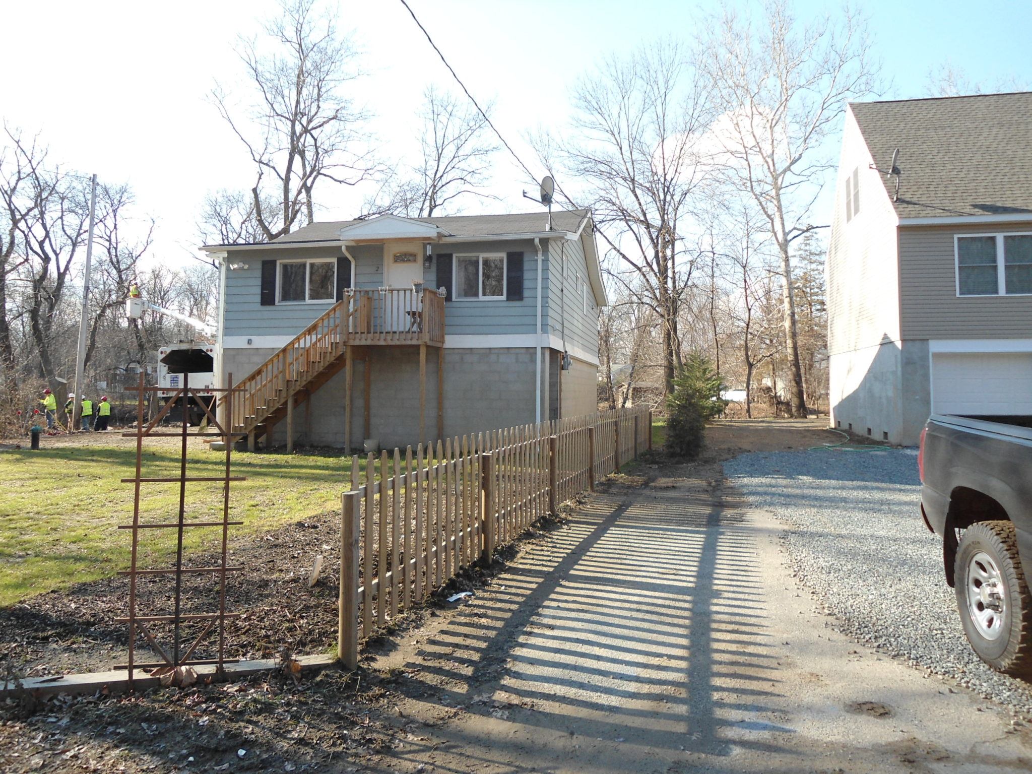 Single story house on tall foundation with fence in back yard.