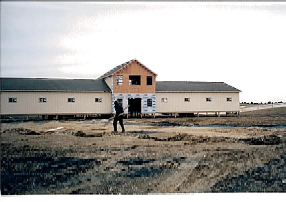 Rolling Stone Farmhouse raised on supports behind worker.