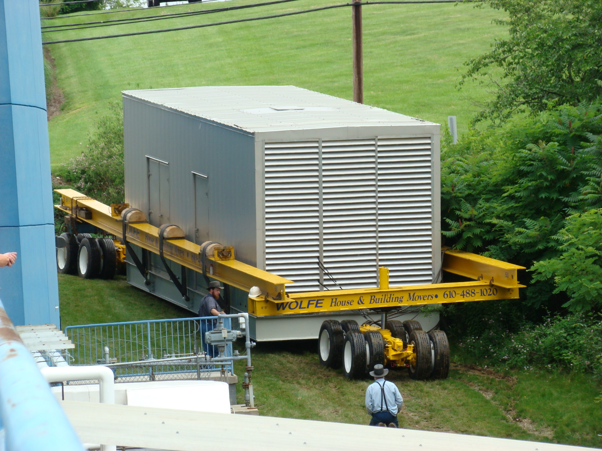 Large generator lifted by dolly moving in grass.