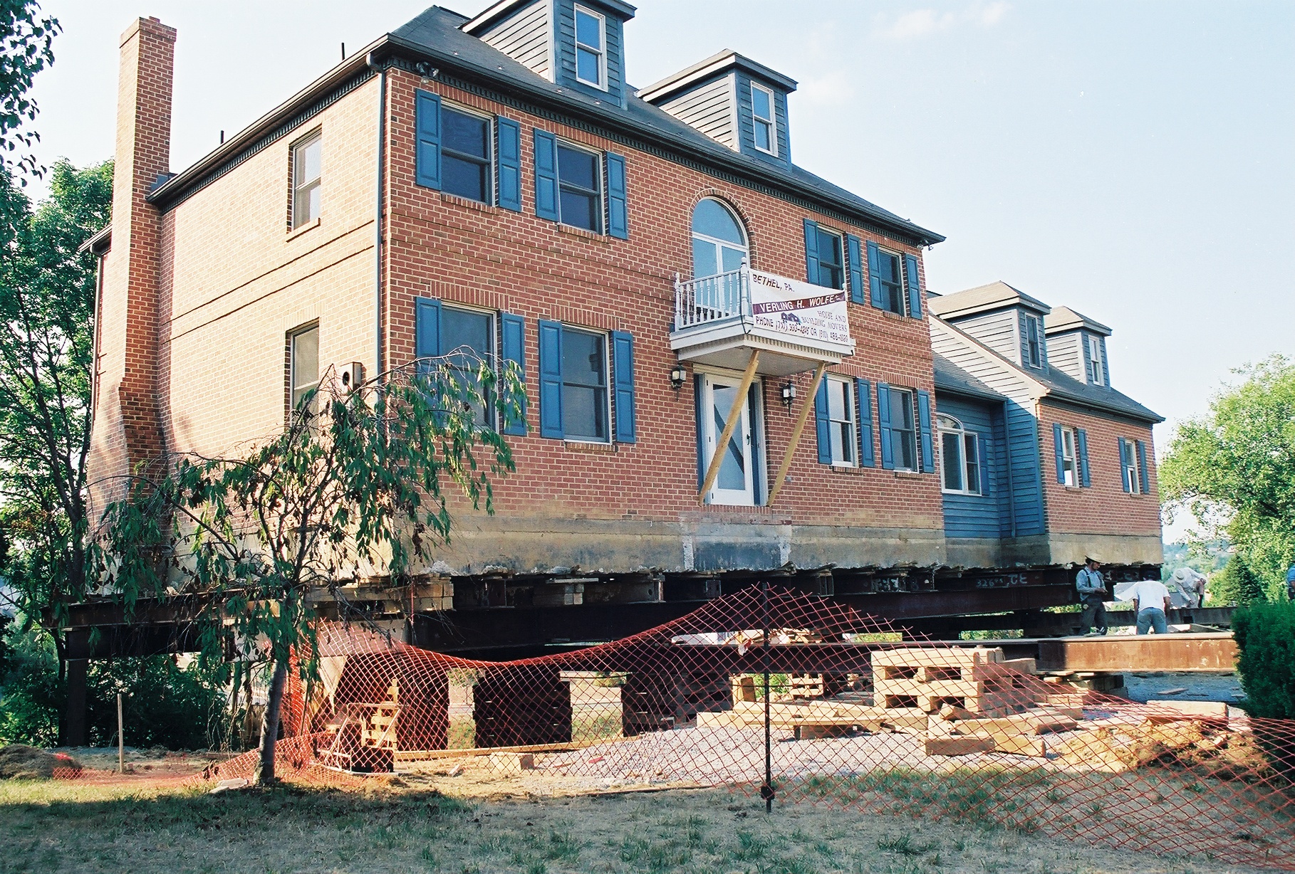 Two story brick house raised on wooden supports.