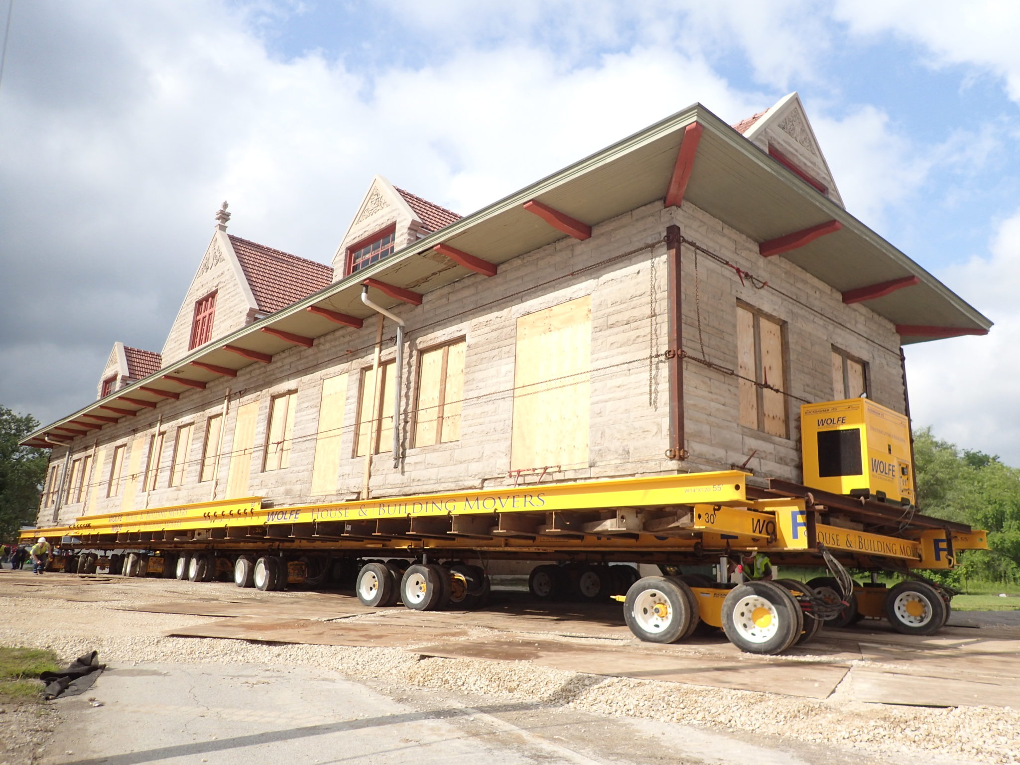 Historic Milwaukee Depot moving on dolly across stone path on top of wooden boards.