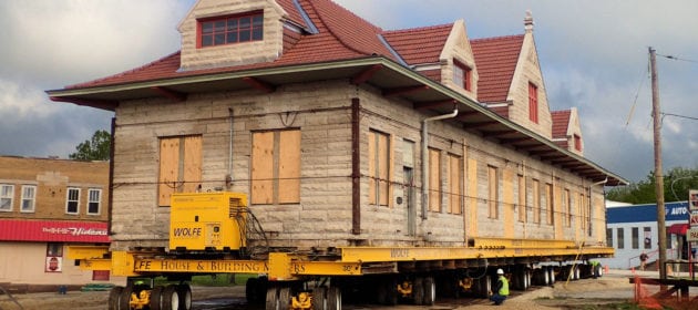 Old Milwaukee Depot on dolly moving across wooden sheets placed down in the dirt.