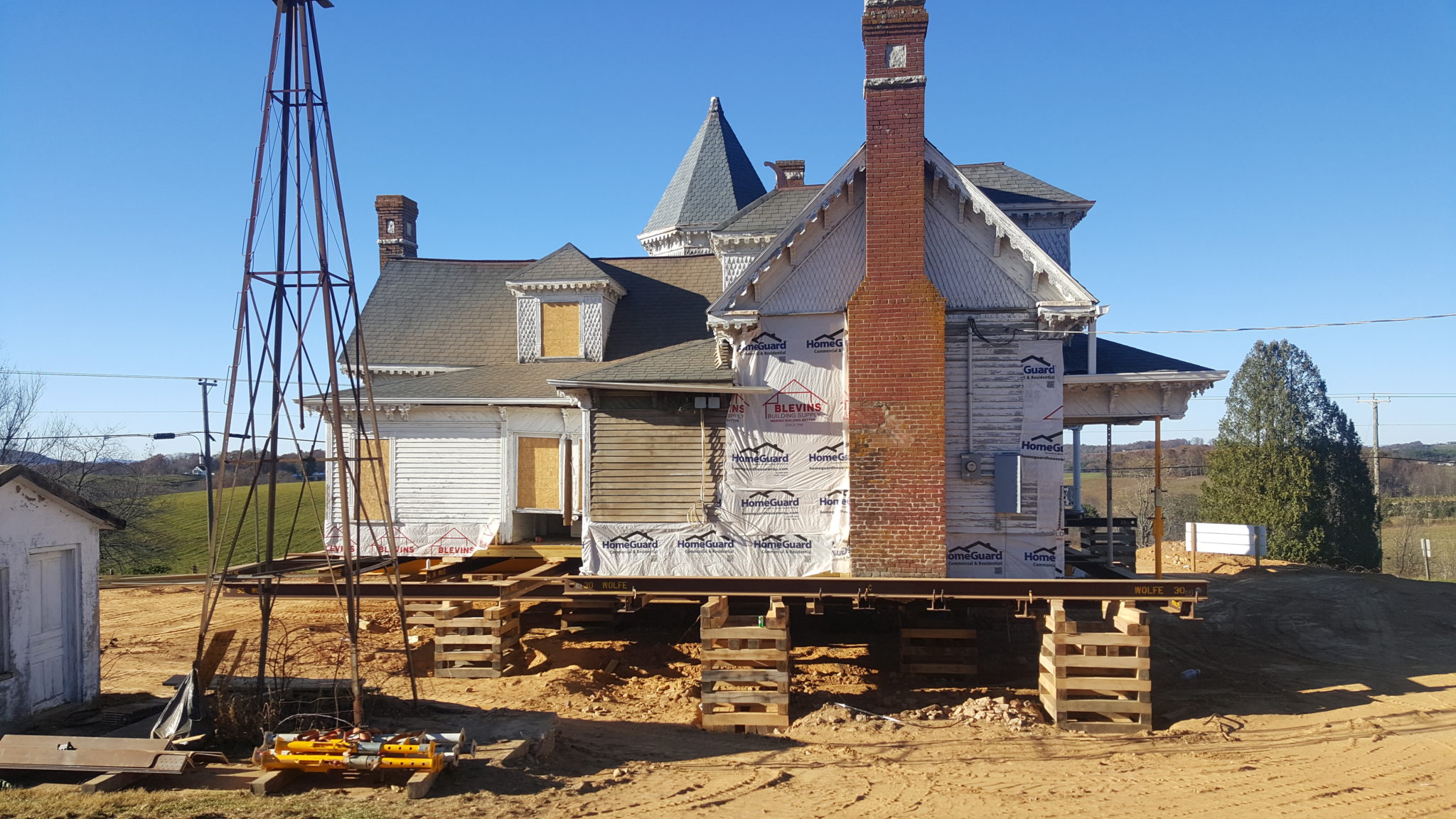 Sidna Allen two story antique house with elaborate trim lifted on wooden supports rear view of brick chimney.