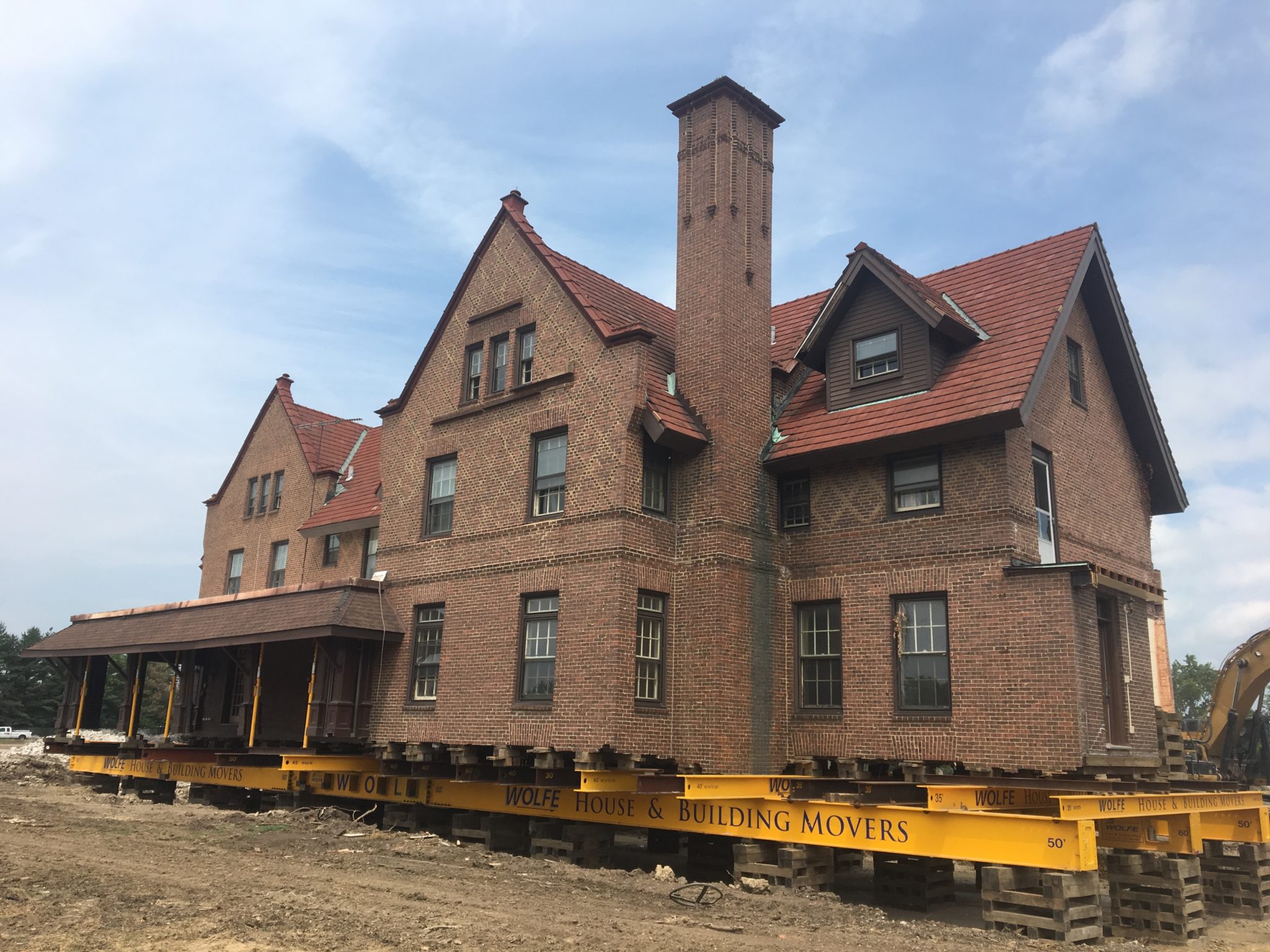 House of Seven Gables, a large red brick mansion, raised on steel beams and wooden supports.