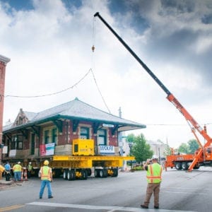 Utility vehicle lifting power line as sturgis depot travels through intersection in small town.