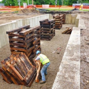 Worker organizing wooden supports in wet conditions.