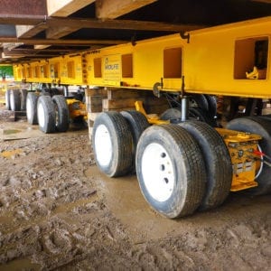 Dolly lifting steel beams in muddy conditions.