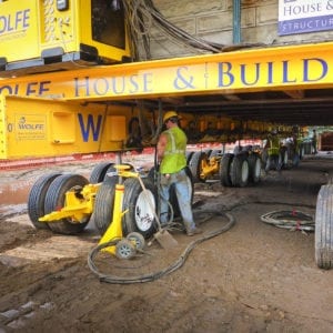 Worker connecting hydraulic lines on a dolly system.