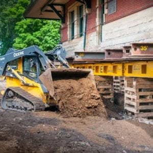 Skid loader excavating around sturgis depot raised on supports.