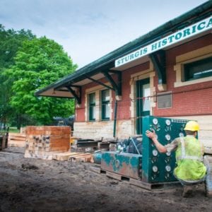 Man at a control panel next to the Sturgis Railroad Depot on steel beams.