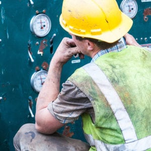 Technician observing various pressure gauges on a control panel.