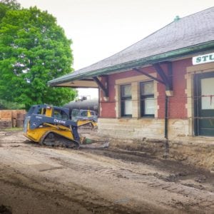 Skid loader drilling a hole into the foundation to make room for additional supports.