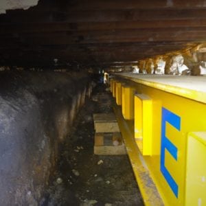 View looking down steel beam underneath building to be supported.