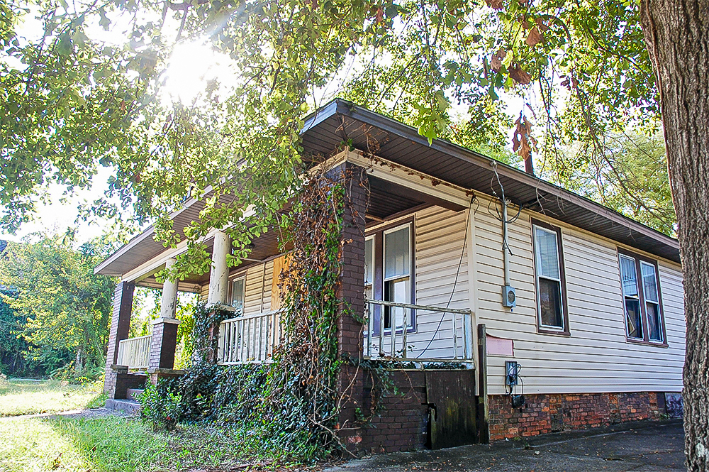 Small, square home with a brick foundation and porch.