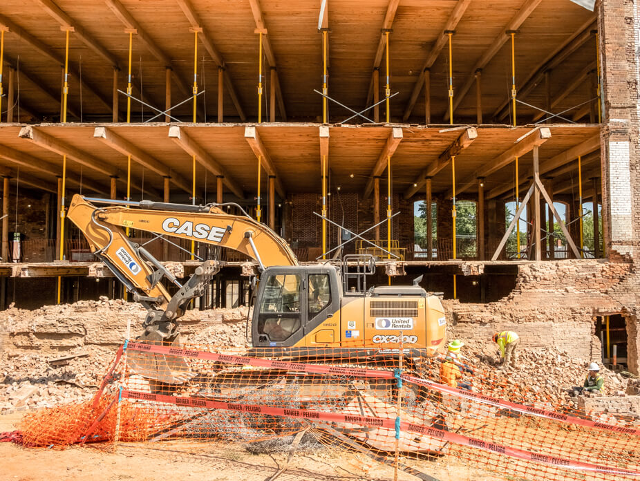 Outer brick wall is demoed while Wolfe supports floors of building