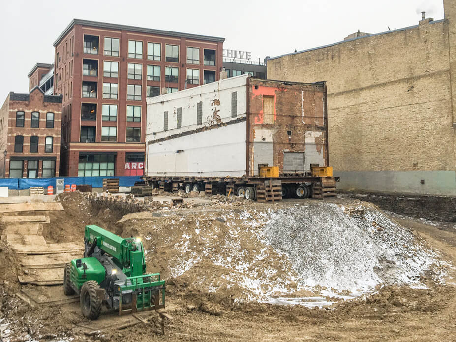 a 22'x66' brick building sits on wheels ready to be moved