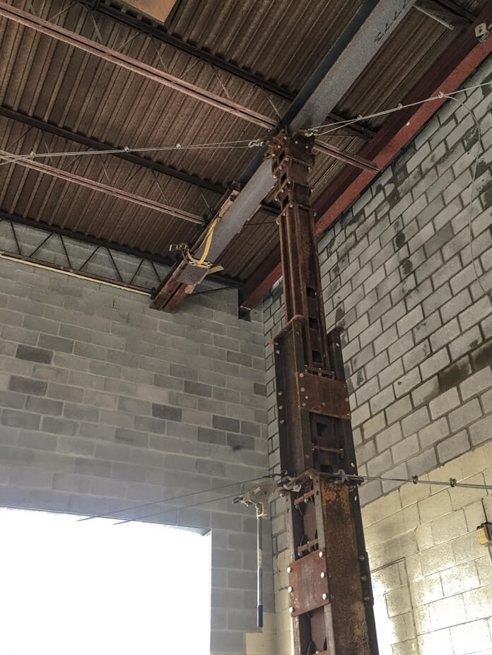 A tower jack supports a corner of the roof while the new wall is finished