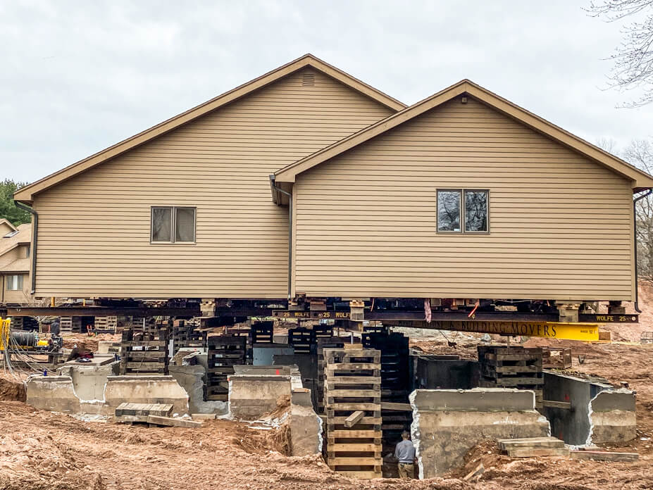 Condominium unit with old foundation under it is lifted on crib piles