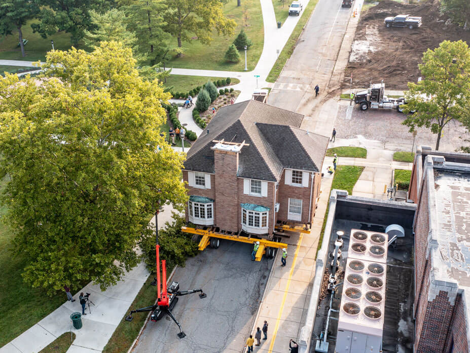 A tree trimmer removes branches from the move route for the May House