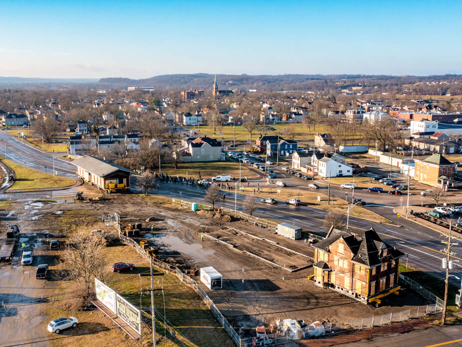 An aerial view of the 2-story Hamilton Depot in the foreground with the 1-story section being moved to location beside it