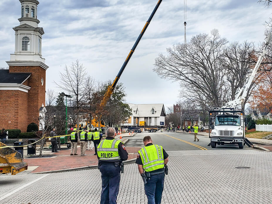 Two policemen watch as the Ivey-Ellington House moves down the road