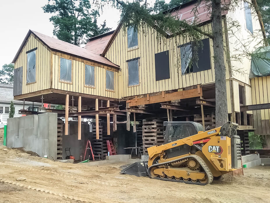 The barn rests on crib piles while crews excavate underneath it