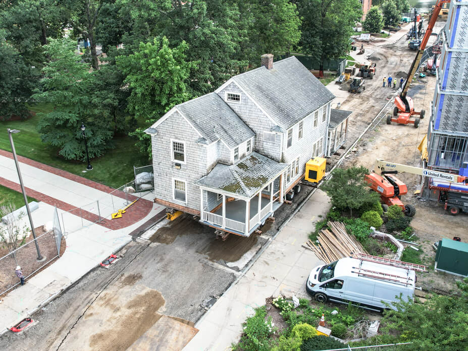 Aerial view of UConn house in street being relocated on dollies
