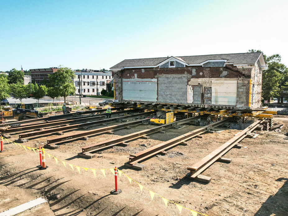 Rear view of Wolfe House Movers roll beam system with New Canaan library building