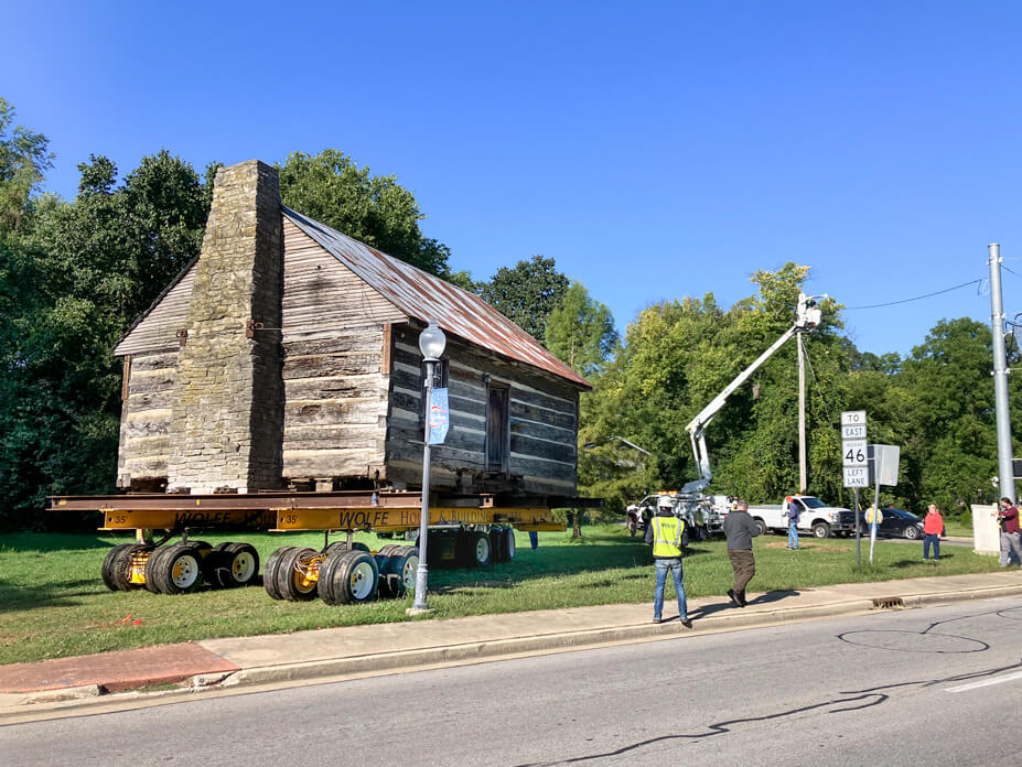 Utility workers lift power lines for historic log cabin relocation