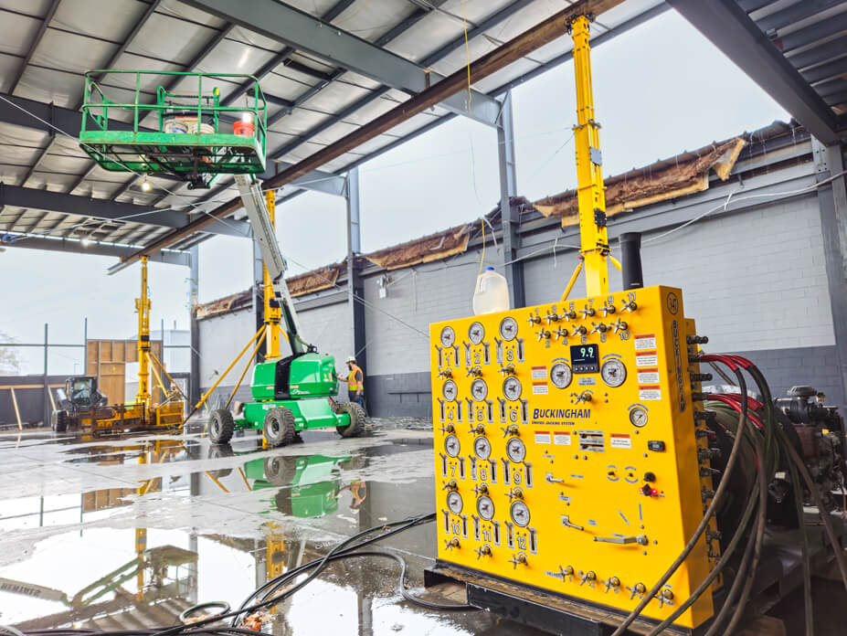 A Buckingham unified jacking machine sits in foreground of Wolfe warehouse roof lift