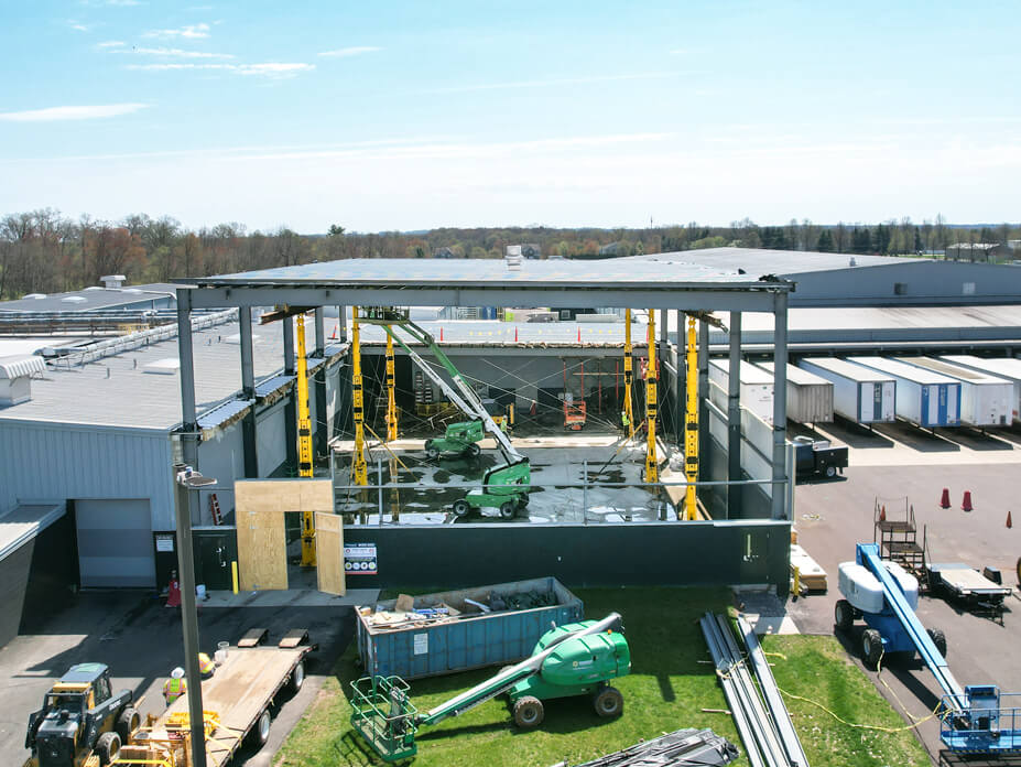 Extended tower jacks support a warehouse roof as Wolfe lifts it 18'