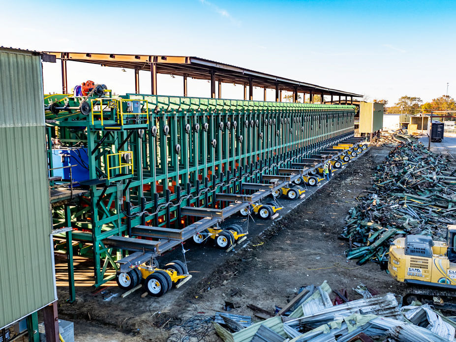 A 225' lumber sorter on dollies is lined up next to the demoed steel of its predecessor