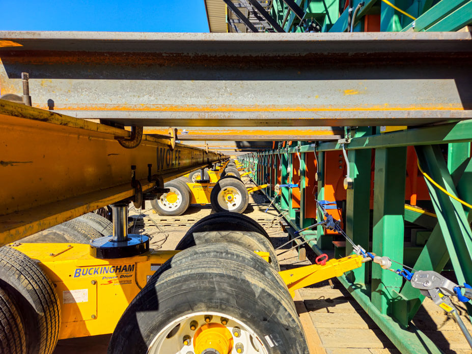 Yellow dollies with steel beams running into a lumber sorter