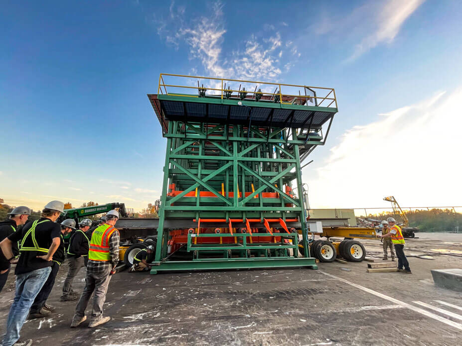 The crews watch as a welder tacks the base of a lumber sorter at final position