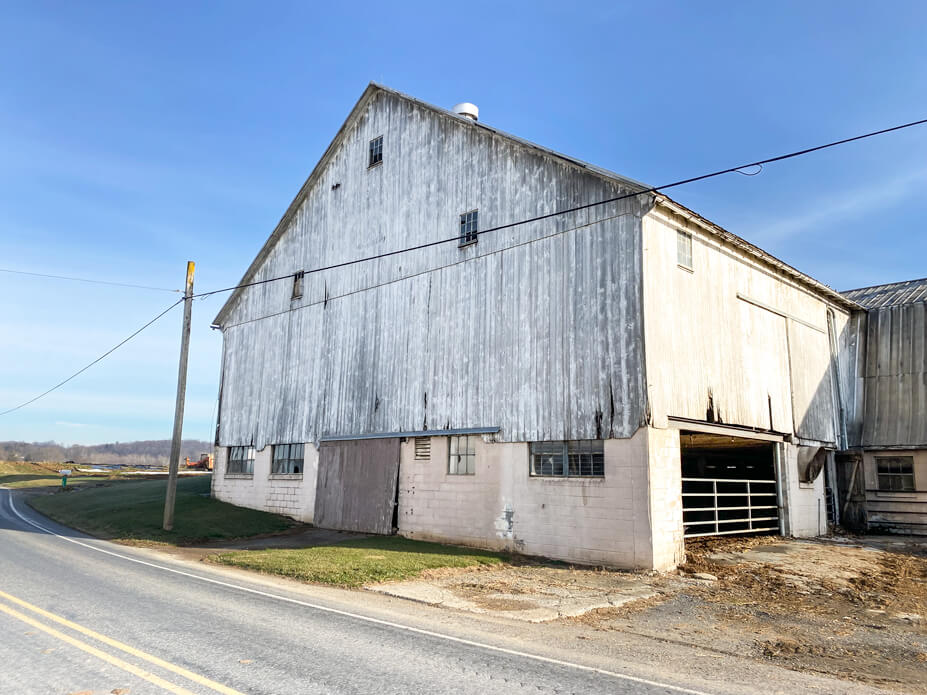 White barn sits a few feet from rural road
