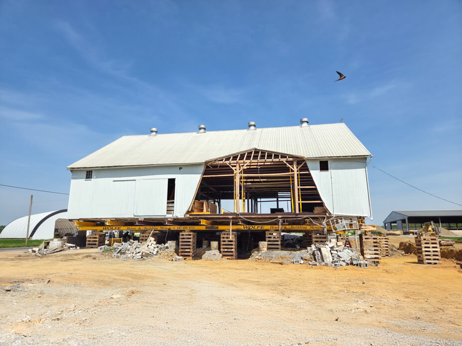 Front view of white timber frame barn on yellow Wolfe steel beams and crib piles