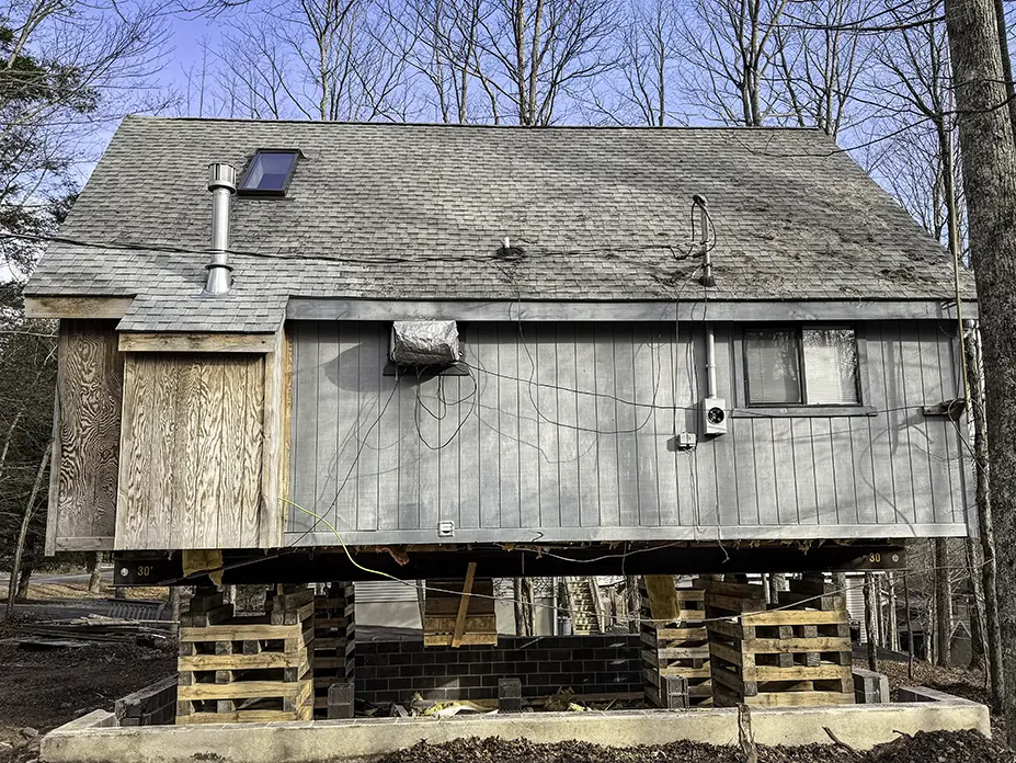 Back side of small gray house sitting on cribbing