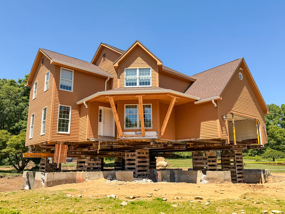 Full photo of the home showing the home on the cribbing and steel beams with shoring posts on the garage