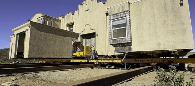 Wolfe foreman uses jack machine to slide house over roller beams